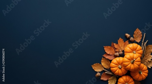 Autumn harvest of pumpkins and fallen leaves arranged on a dark blue surface