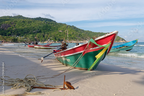 Traditional colorful wooden fishing boat anchored on sandy beach