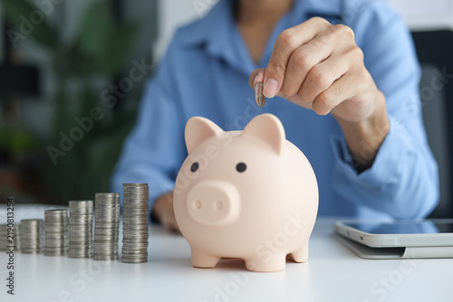 Fotografie A person putting a coin into a piggy bank