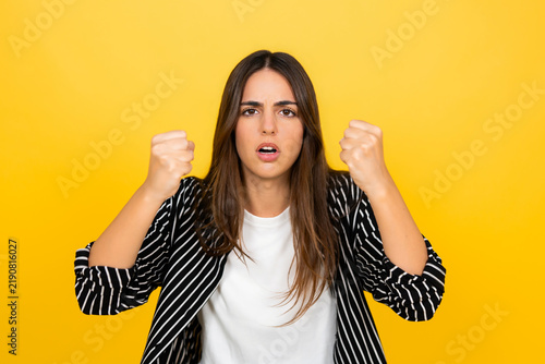 Quadro su tela Young woman showing intense frustration and anger, clenching fists while looking