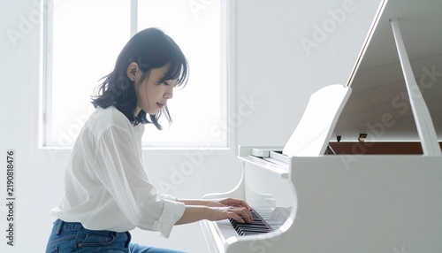 Tapety artystyczne 明るい部屋でラフな服装でピアノを弾く女性