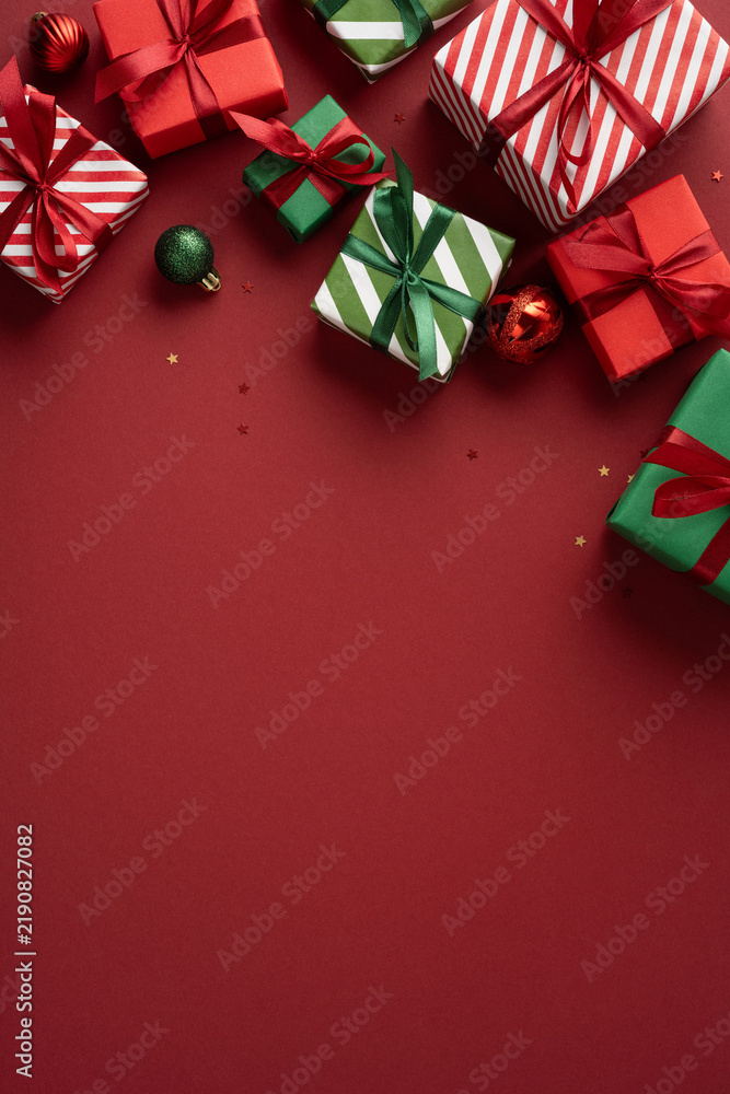 Naklejka premium Merry Christmas and happy New Year with wrapped presents and ornaments on vertical burgundy red background