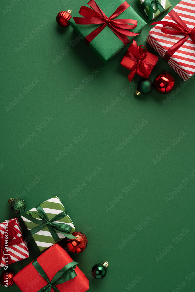 Obraz premium Christmas presents and ornaments on vertical green background with ribbons for Merry Christmas and Happy New Year