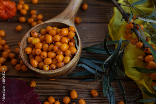 Konstfotografi Ripe sea buckthorn berries in wooden scoop on rustic table