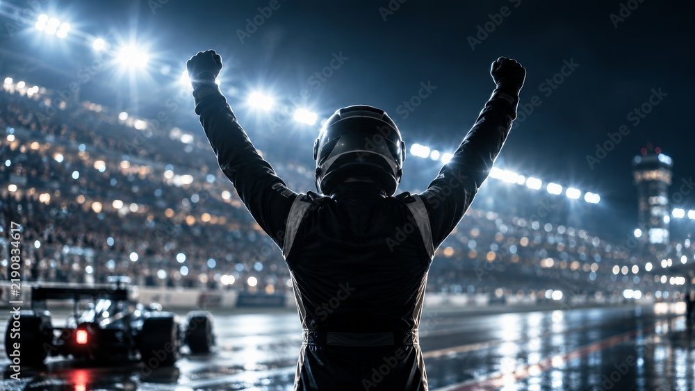 Fototapeta premium Silhouette of a race car driver celebrating a victory against bright stadium lights.