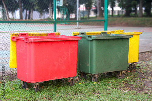 Foto Row of large color-coded plastic trash cans for public waste management