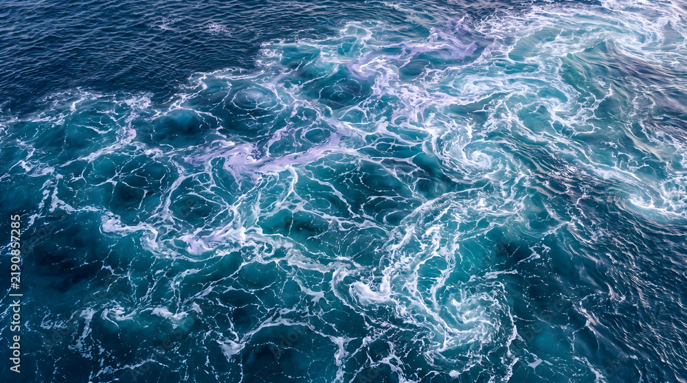 Fototapeta premium Dynamic Aerial View of Powerful Ocean Currents and Foaming Whirlpools, Creating Intricate Blue and White Water Patterns, Illustrating the Raw Force of Nature