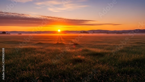 Panoramic sunset over misty meadow landscape