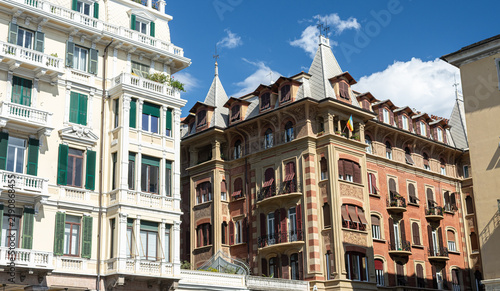 Foto Fachadas de elegantes edificios históricos europeos con balcones, postigos verdes y detalles arquitectónicos bajo un cielo azul soleado