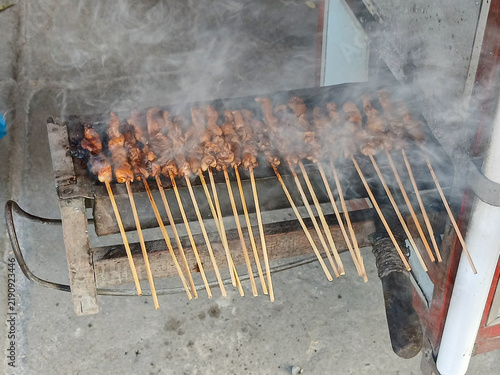 Traditional Indonesian chicken or meat satay grilling over charcoal fire with smoke