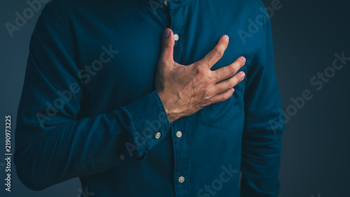 фотографія Adult man is clutching his chest due to a sudden heart attack and experiencing chest pain