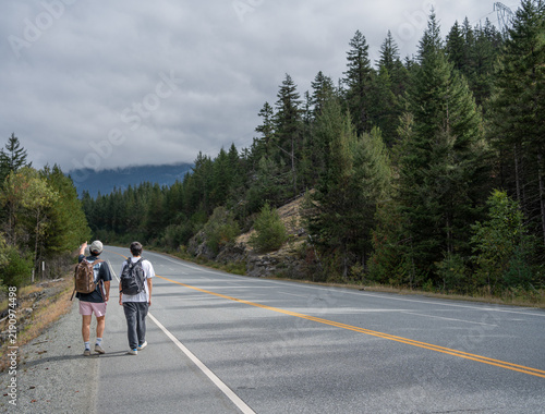 Two friends walking along the side of the road
