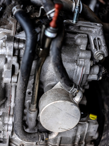 Close up of a dirty car engine block with hoses and mechanical parts