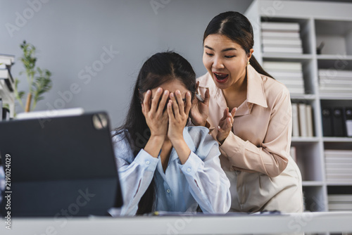 Asian businesswomen working in office, manager yelling at stressed employee covering face with hands, conflict at work, stress, frustration, emotional pressure, bullying.