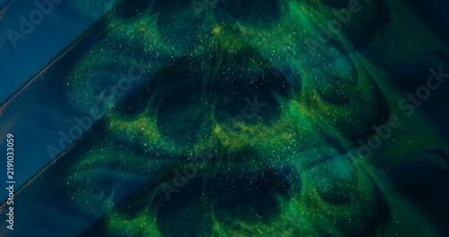 Sparkling splash. Defocused glitter ink. Green blue purple color glimmer art texture shiny fluid spilling on abstract background.