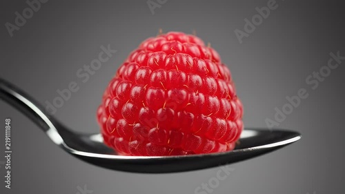 Single Red Raspberry On A Silver Spoon With Dark Grey Background Studio Shot