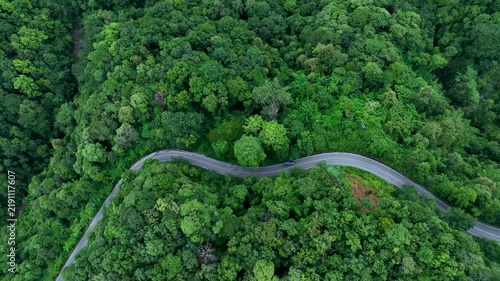 Aerial forest road with car creating abstract background for electric vehicle, ESG, sustainability and green investment business concepts.