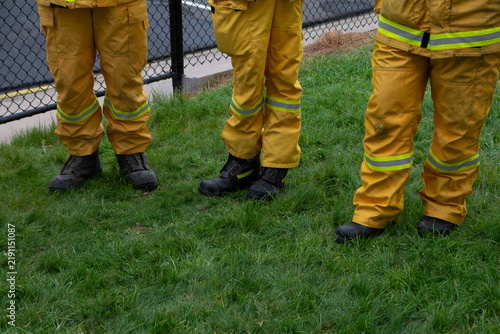 legs and boots of firefighters wearing yellow protective uniforms