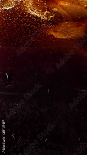 Slow motion vertical pouring cola with ice cubes and bubbles, soft drink