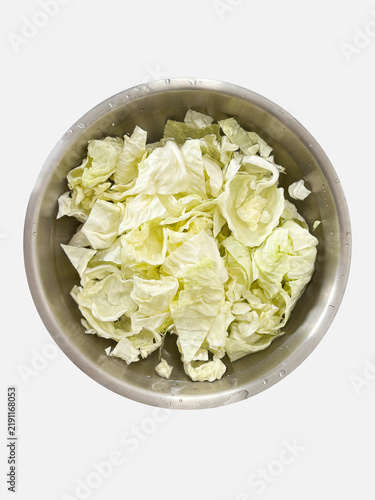 Top view of chopped fresh green cabbage leaves washed in a stainless steel bowl, isolated on a white background. Essential ingredient for healthy cooking and food preparation.