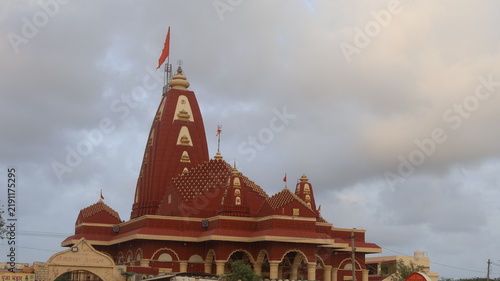 Obraz na płótnie Majestic Red Hindu Temple Architecture with Vibrant Orange Flag Against Cloudy S