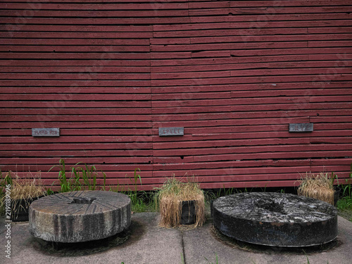 Foto Old stone millstones displayed in front of a red barn wall