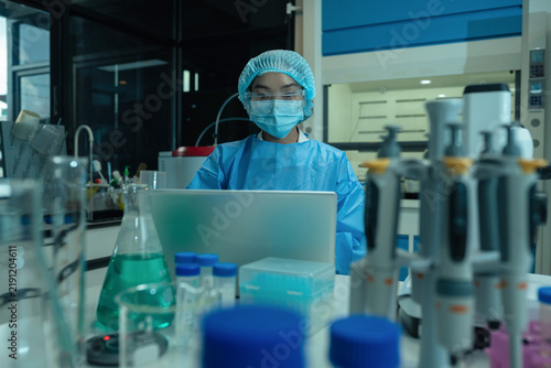 Fotografie Biomedical scientists in PPE analyze chemical samples a microscope, advancing vaccine development, biotechnology, medical research, disease prevention, and healthcare innovation