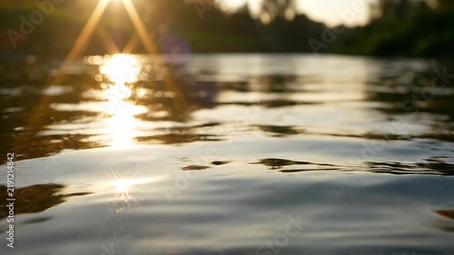 Serene River Surface with Golden Sunset Reflections and Gentle Ripples