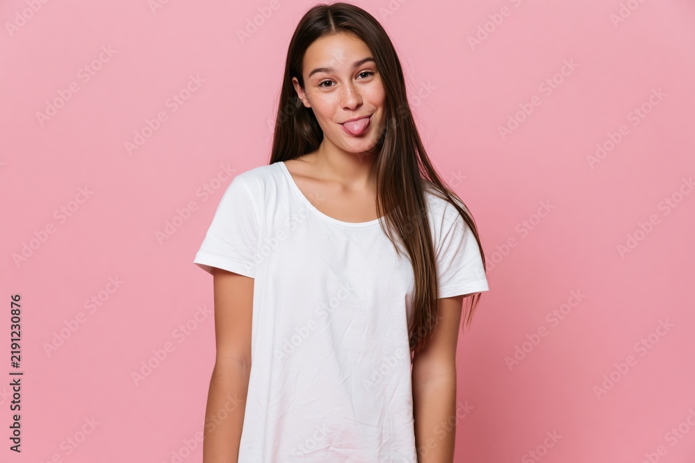 Obraz premium The Woman in White Tshirt Smiling Playfully Against Pink Background