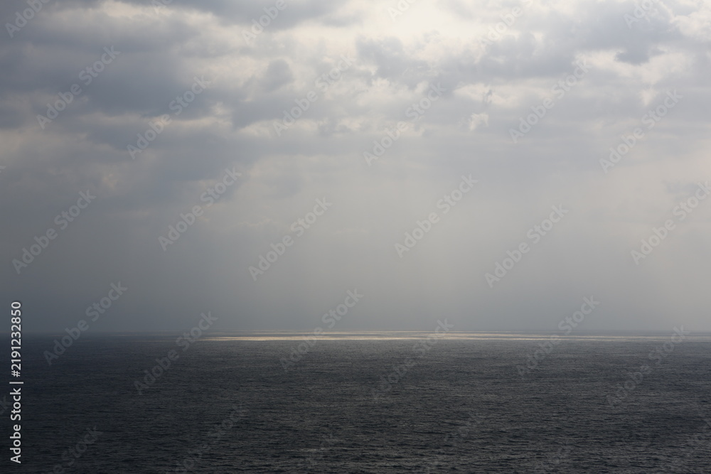 Fototapeta premium Sunlight breaks through dark clouds over the sea.