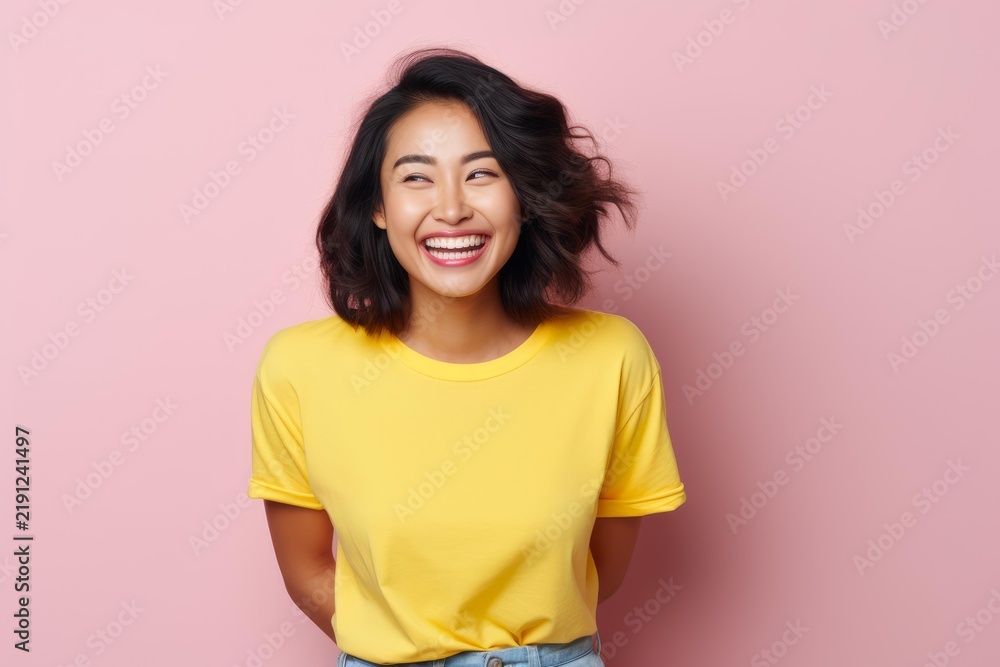 Fototapeta premium Young asian woman smiling broadly, expressing joy and positive emotions on a pink background
