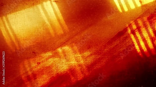 Vintage cinematic light leak and film grain texture on red background. Abstract retro overlay with glowing orange reflections and scratched analog surface for creative video editing.