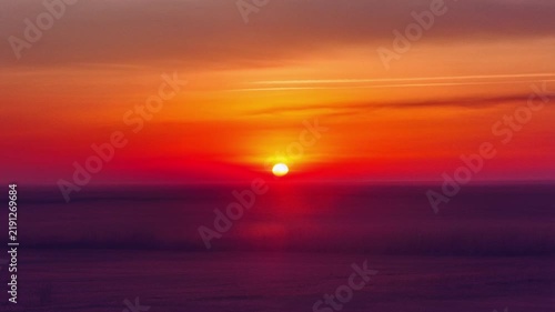 Cinematic sun setting over a flat horizon with vibrant orange and purple gradient sky, capturing a peaceful dawn or dusk atmosphere.