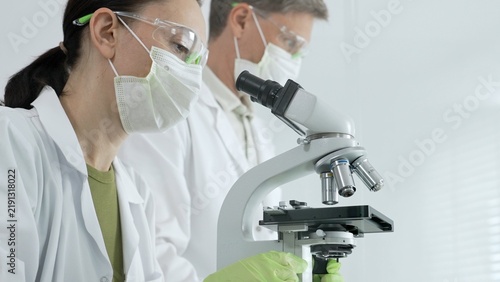Obraz na płótnie Female scientist wearing protective gear performing research using a microscope,