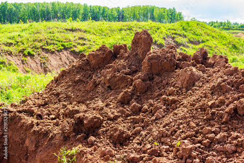 Canvastavla Large pile of freshly excavated raw clay soil on a green meadow, dug up by heavy