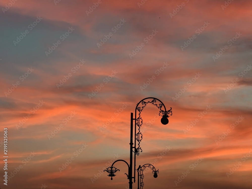 Obraz premium Ornate street lamp silhouette beneath a colorful sunset sky