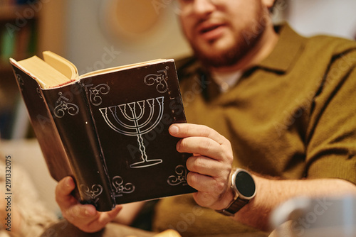 Quadro su tela Caucasian young adult man holding Jewish prayer book with menorah symbol during family celebration