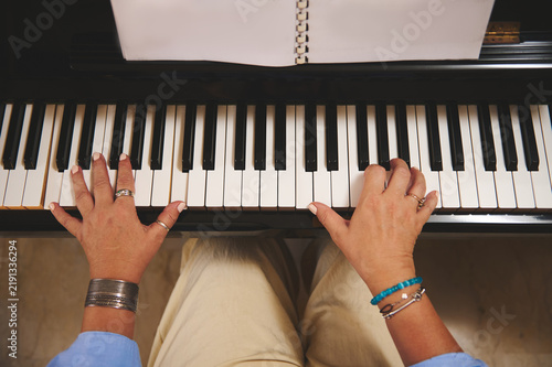 Fotografie Woman playing piano with sheet-music, close-up of hands on keys and rings