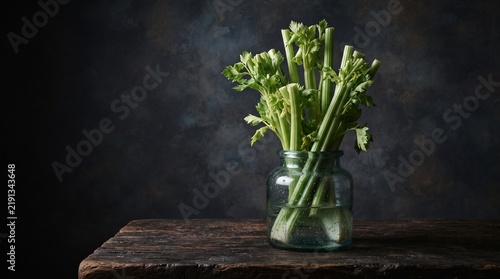 Artistic still life featuring sculptural celery stalks in a vintage glass vase, combining botanical elegance, dramatic lighting and an unconventional food photography concept.