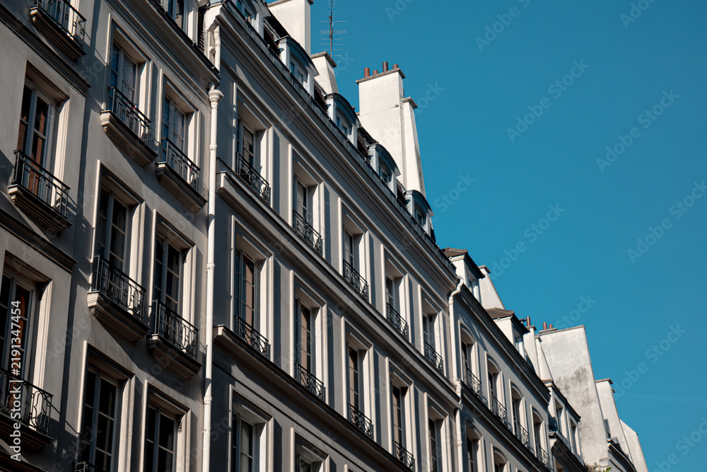 Obraz premium Haussmann architecture in paris featuring classic building facades, many windows, and dormer roofs against a clear blue sky