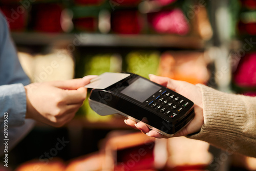 Foto Close up shot of unrecognizable customer paying with contactless credit card on POS payment terminal held by cashier
