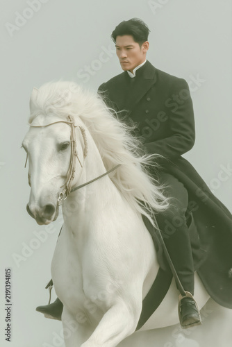 Elegant Man Riding White Horse: A distinguished man in formal attire elegantly rides a magnificent white horse with a flowing mane, embodying a sense of power and sophistication.