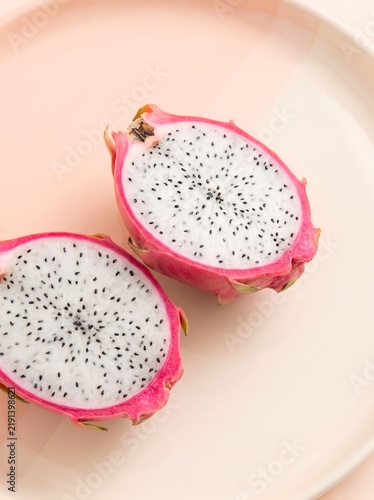 Fresh dragon fruit halves on a pastel pink plate
