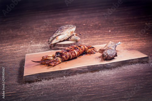Foto Grilled glazed squid on rustic board