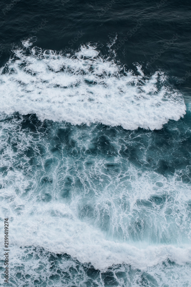 Obraz premium Natural background of blue ocean waves with white sea foam and turquoise water, abstract natural seascape poster