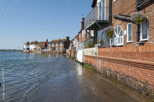 Flooded road at high tide with houses at Bosham Quay, West Sussex, England