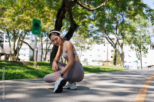 Obraz na płótnie Asian woman runner experiencing sudden ankle pain during outdoor jogging in a pa
