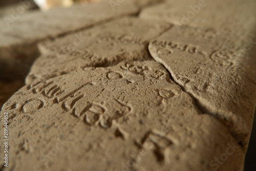 Ancient Javanese script engraved on historical stone inscription tablet in museum close up