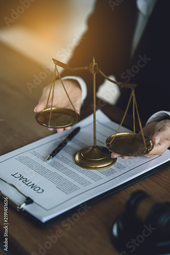 Lawyers reviewing and signing a legal contract at a desk with a gavel and scales of justice, representing legal consultation, agreement process, and professional law services.