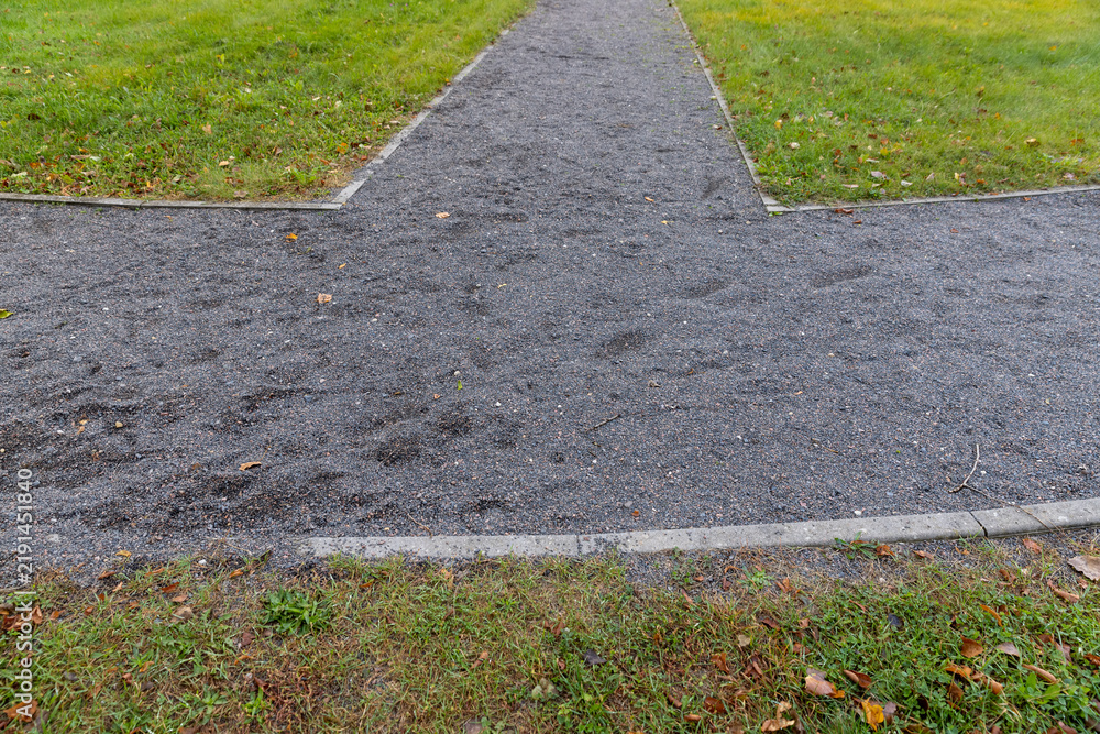 Obraz premium Grey gravel of a garden path next to the lawn, no person
